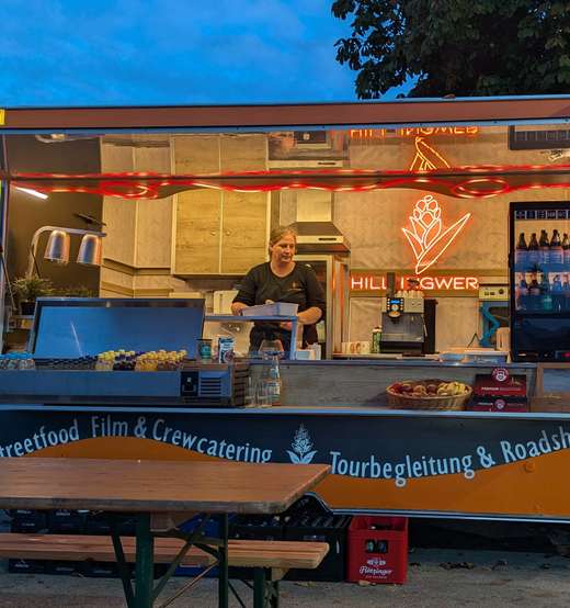 Köchin im beleuchteten Foodtrailer am Abend