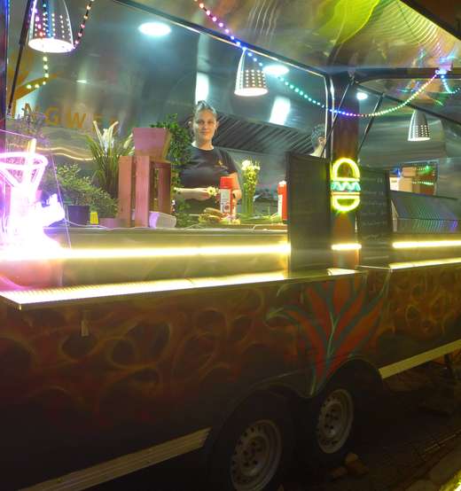 Foodtrailer am Abend mit Lichterkette und Cocktail-Neonschild