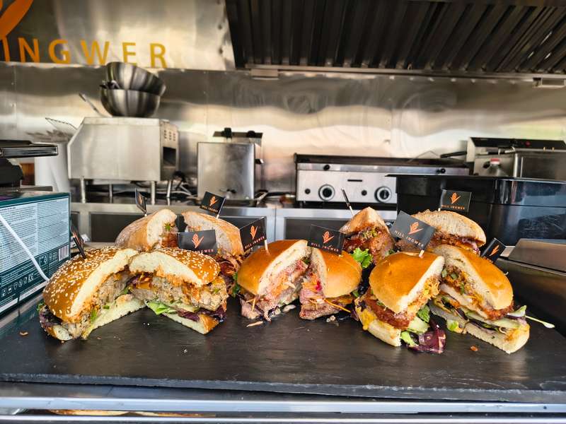 Halbierte Burger mit Käse und Salat auf einer Schieferplatte vor der Küche im Foodtrailer