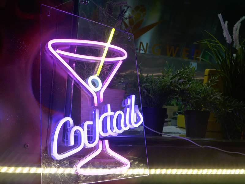 Neonschild „Cocktails“ in Lila im Foodtrailer, dahinter Pflanzen und Hill-Ingwer-Logo