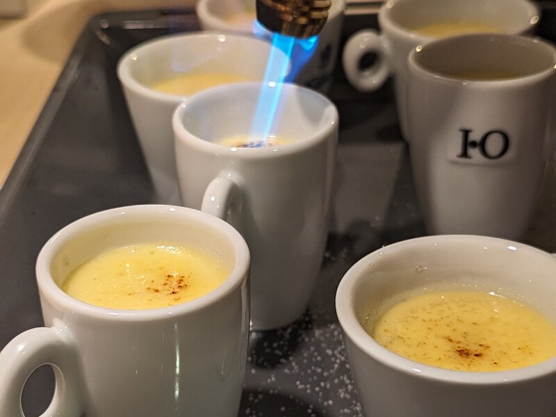 Crème brûlée in Espressotassen wird mit dem Brenner abgeflammt