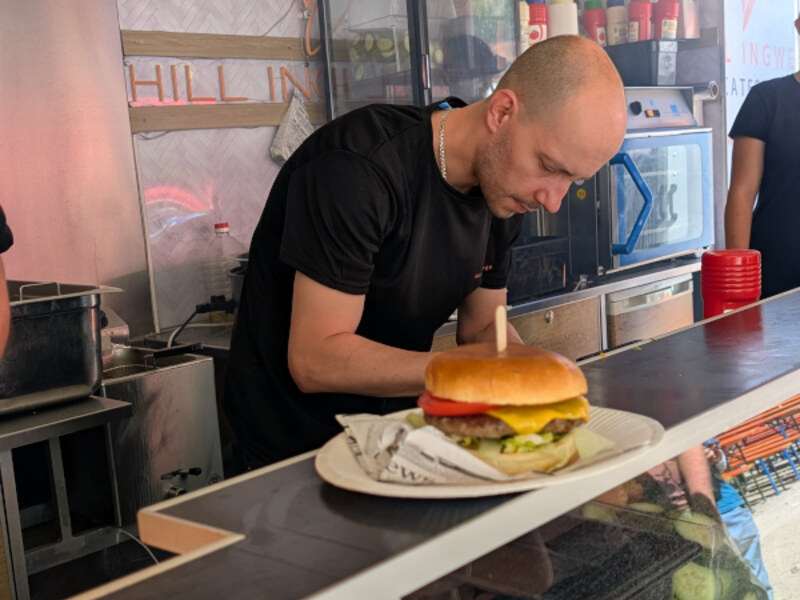 Koch richtet im Foodtrailer einen Burger auf einem Teller an