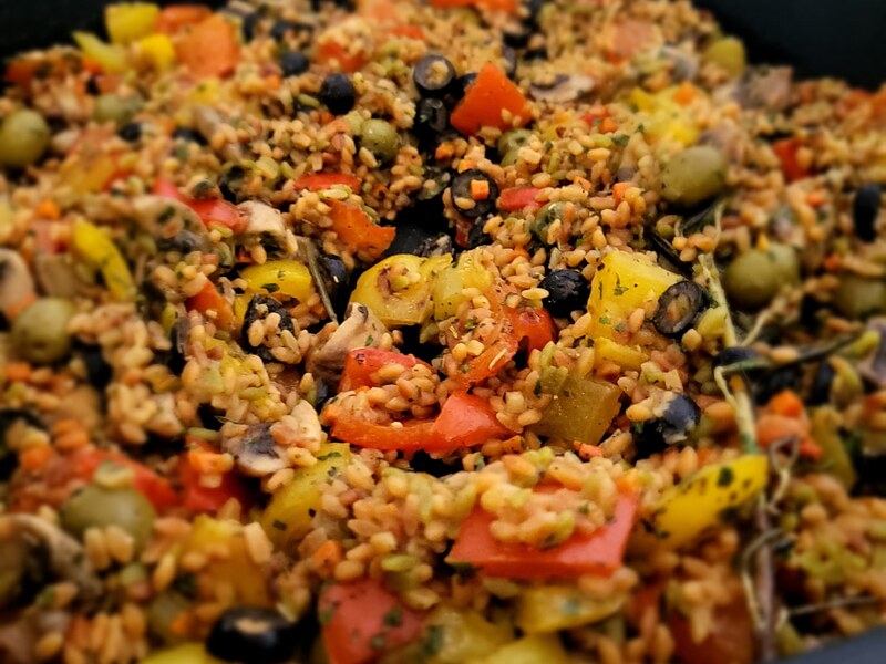 Getreidesalat mit Oliven, Paprika und Kräutern in Nahaufnahme