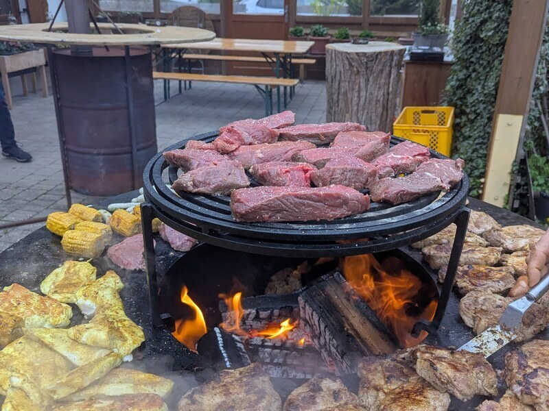 Rindersteaks, Maiskolben und Hähnchen auf dem offenen Feuer eines Grills