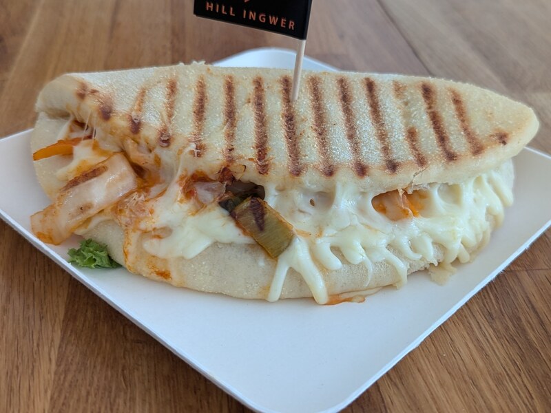Gegrilltes Sandwich mit geschmolzenem Käse und Kimchi auf einem Teller
