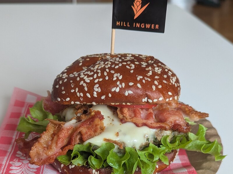 Burger im Sesam-Bun mit Speck, Käse und Salat, dekoriert mit Hill-Ingwer-Fähnchen